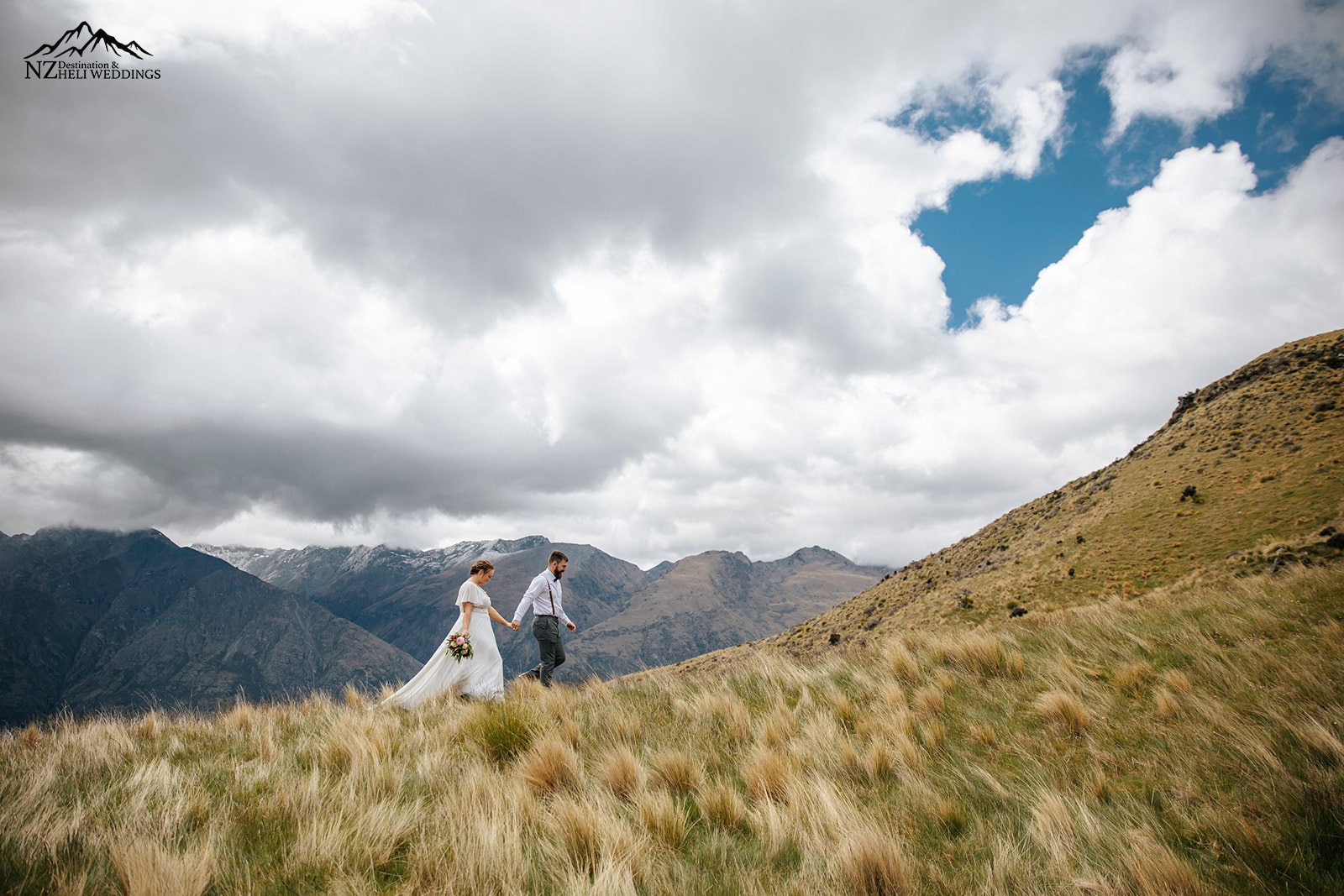 Bride and groom walking on mountain ridge