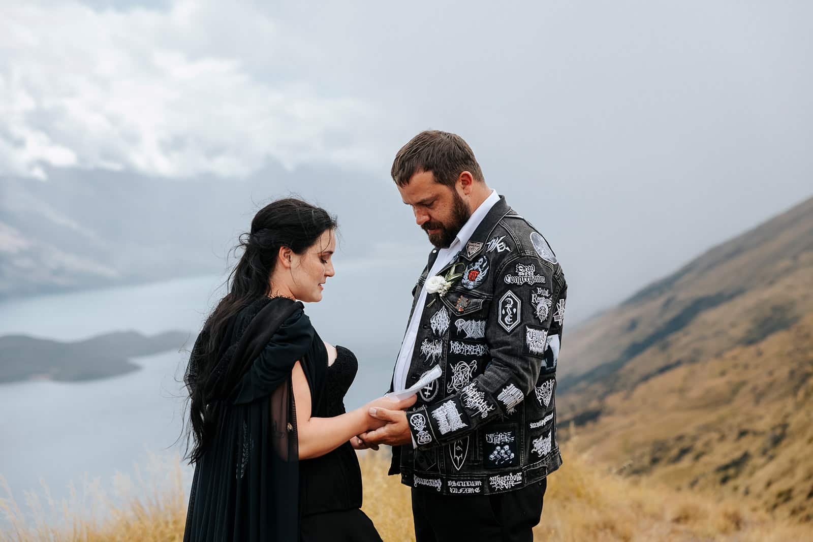 Alternative wedding with heavy metal theme and bride wearing black dress and groom with black jeans jacket and heavy metal badges