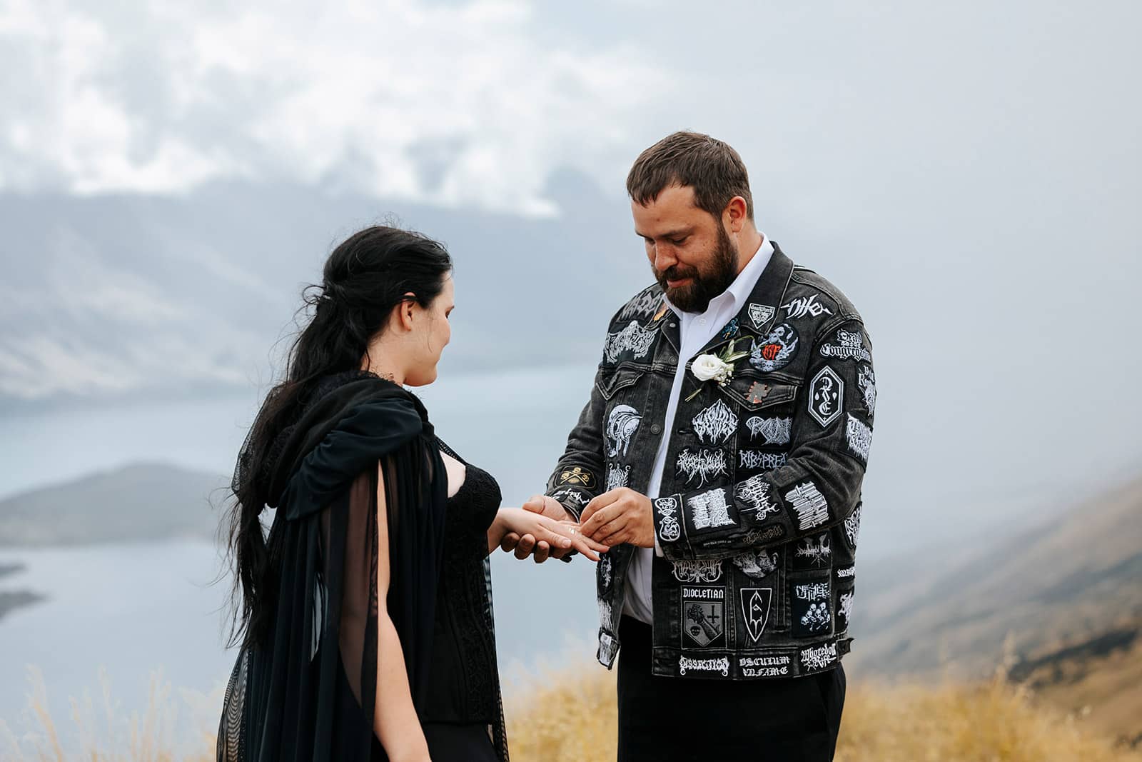 Alternative wedding with heavy metal theme and bride wearing black dress and groom with black jeans jacket and heavy metal badges